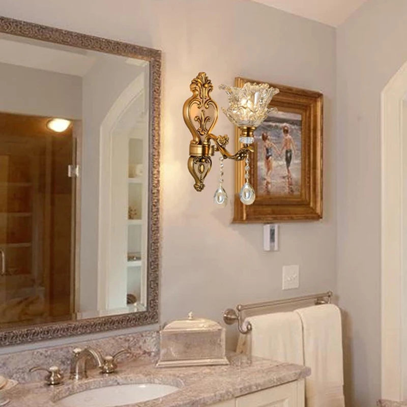 Applique murale classique dorée avec abat jour en verre et pampilles en cristal installée au mur dans une salle de bain élégante