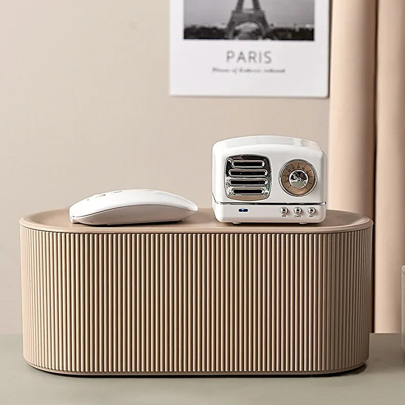 Boite de rangement multiprise beige posée sur un meuble avec objets électroniques décoratifs