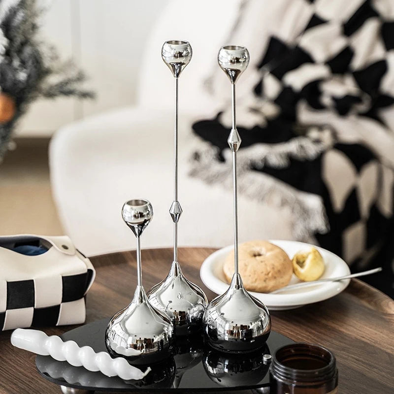 Ensemble de bougeoirs décoratifs en métal argenté posés sur une table avec des éléments de décoration.