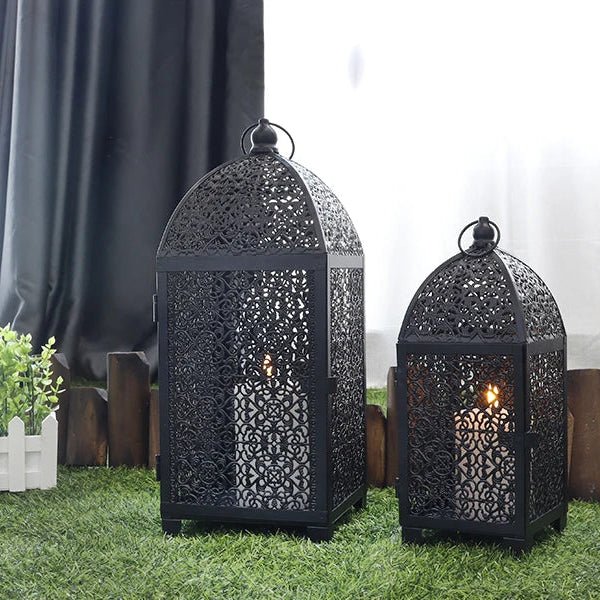 Deux lanternes décoratives noires en métal ajouré posées dans un décor extérieur.