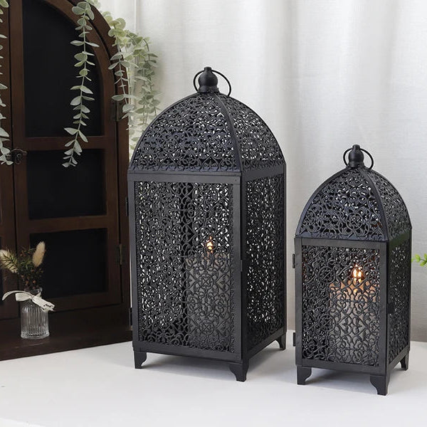 Lanternes décoratives noires posées sur une table avec éléments végétaux.