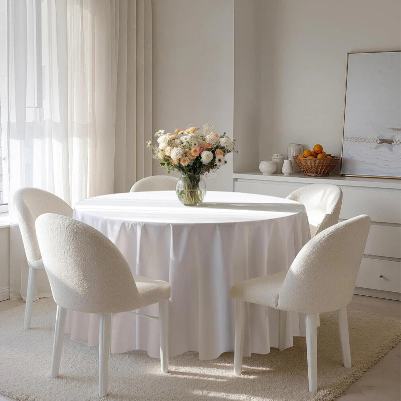 Nappe ronde blanche installée sur table de salle à manger avec décoration florale.