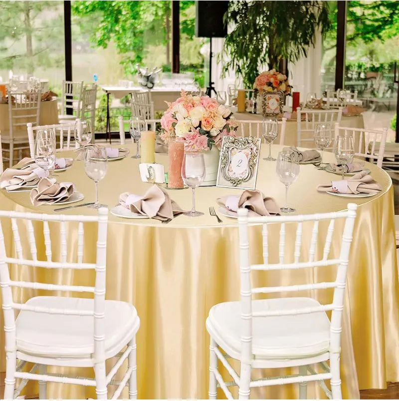 Nappe ronde couleur champagne installée sur table de mariage avec décoration florale.