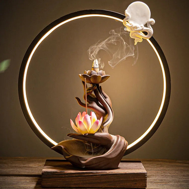 Porte encens lotus avec main sculptée et halo lumineux créant une ambiance zen.