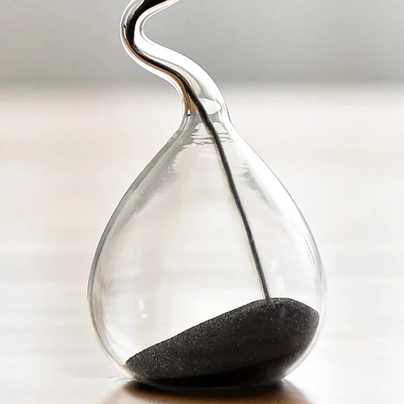 Sablier décoratif en verre transparent avec sable noir, au design moderne.