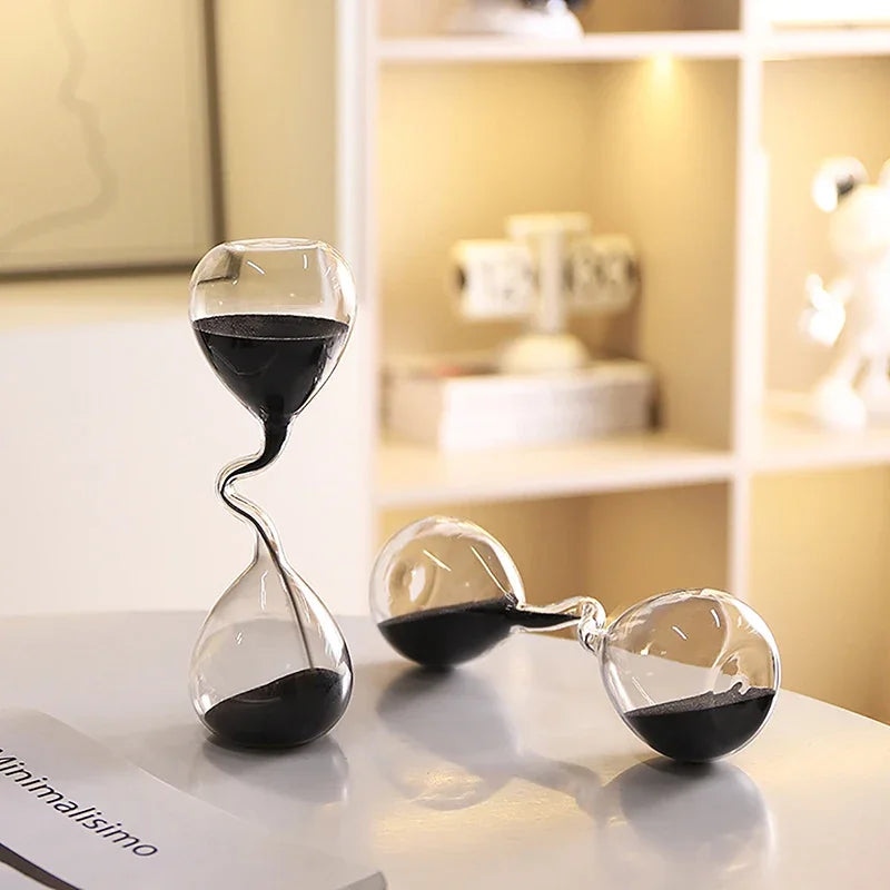 Plusieurs sabliers décoratifs en verre avec sable noir, utilisés comme objets de décoration.