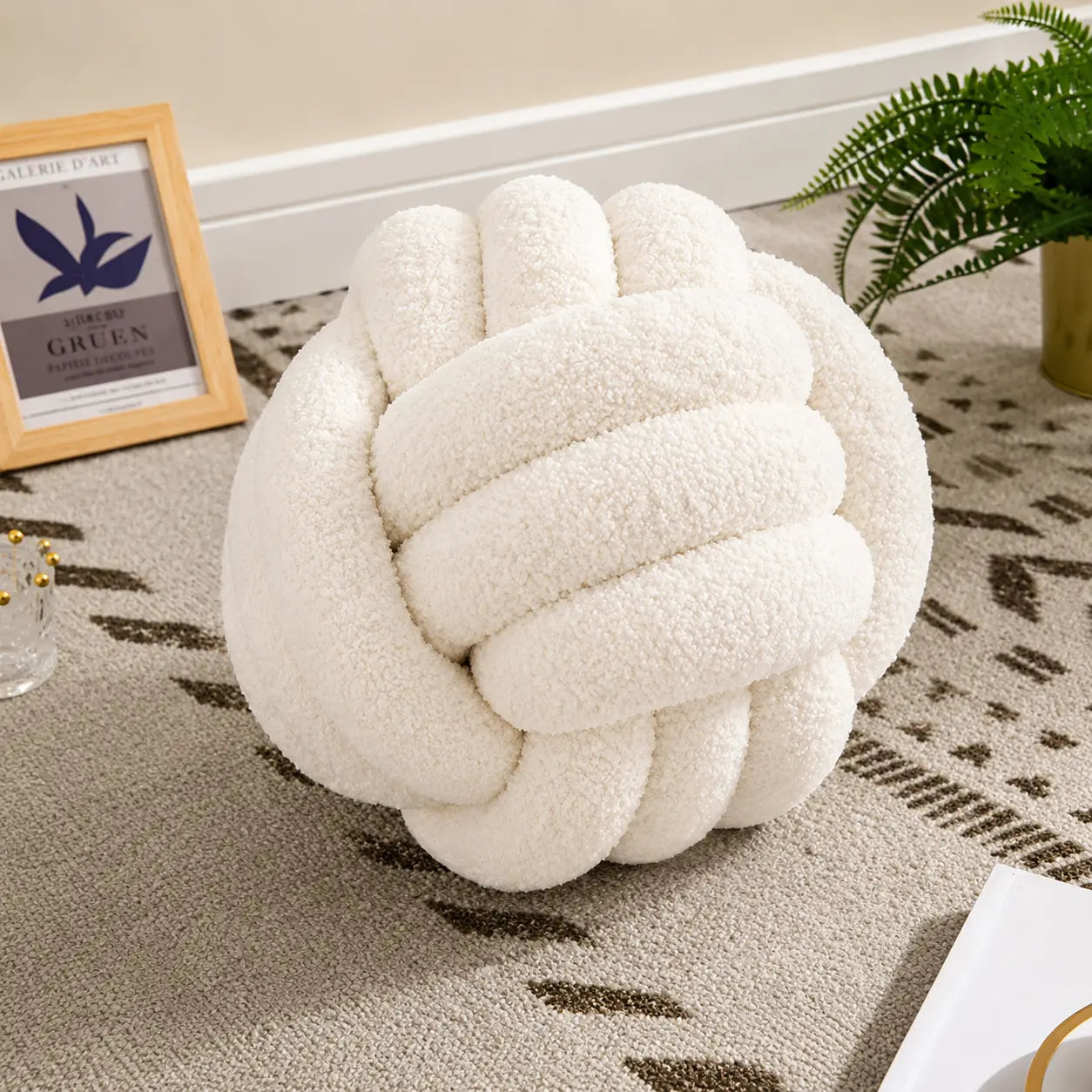 Coussin noeud blanc crème en tissu bouclé décoratif sur tapis beige