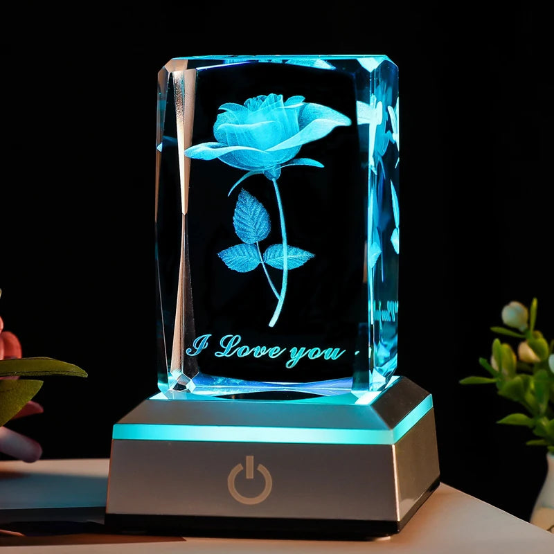 Bloc de cristal rose 3D illuminé en bleu turquoise, présenté avec des fleurs naturelles en arrière-plan