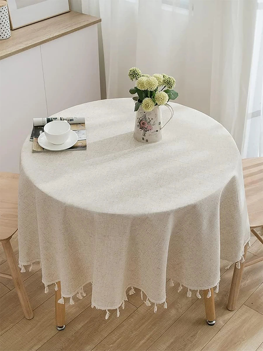 Nappe en lin beige naturel avec franges décoratives sur table ronde en bois