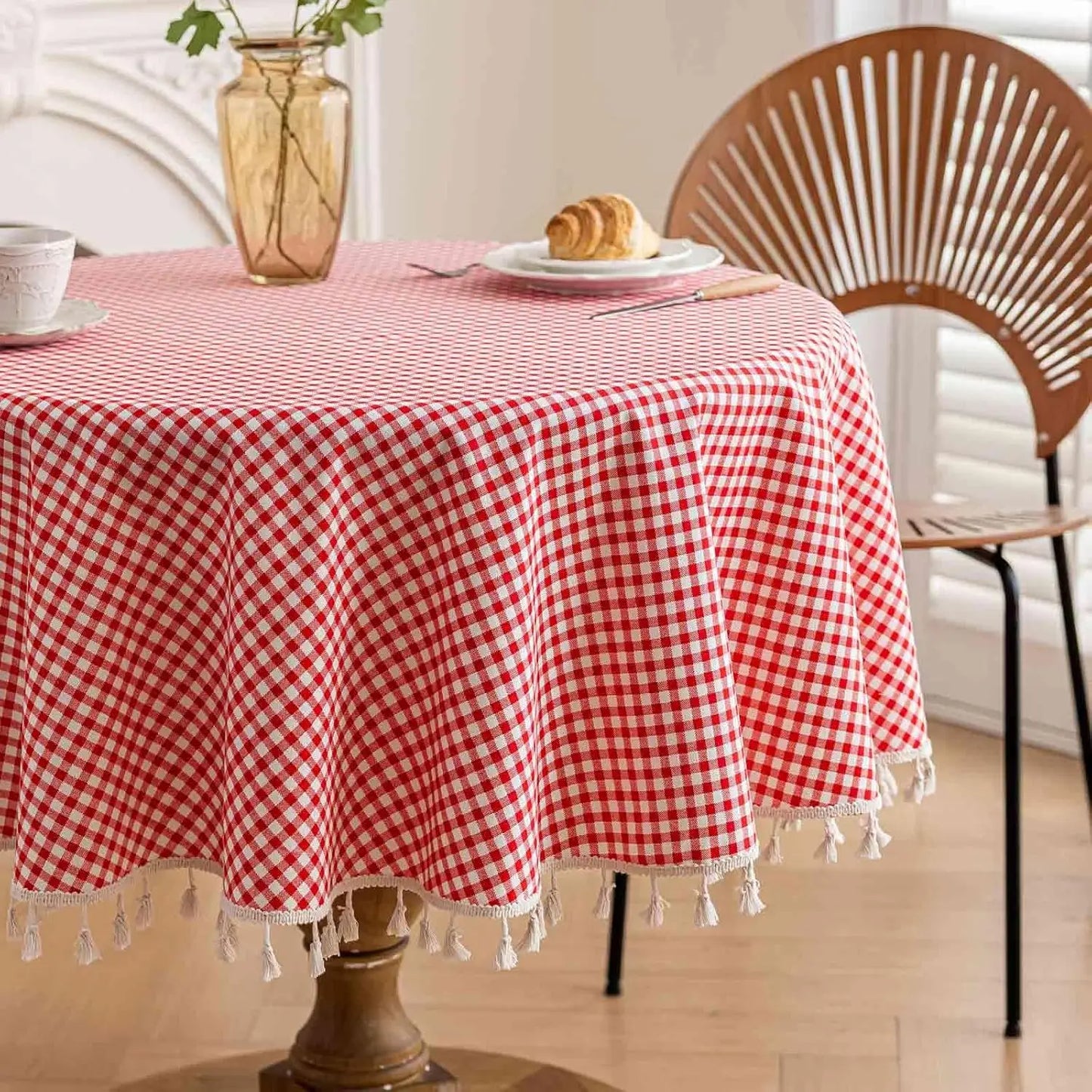 Gros plan d’une nappe vichy rouge retombant sur le bord d’une table ronde