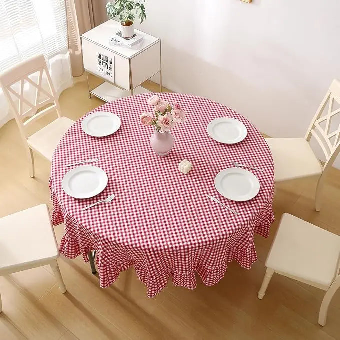 Vue du dessus d’une table ronde avec nappe vichy rouge et vaisselle blanche