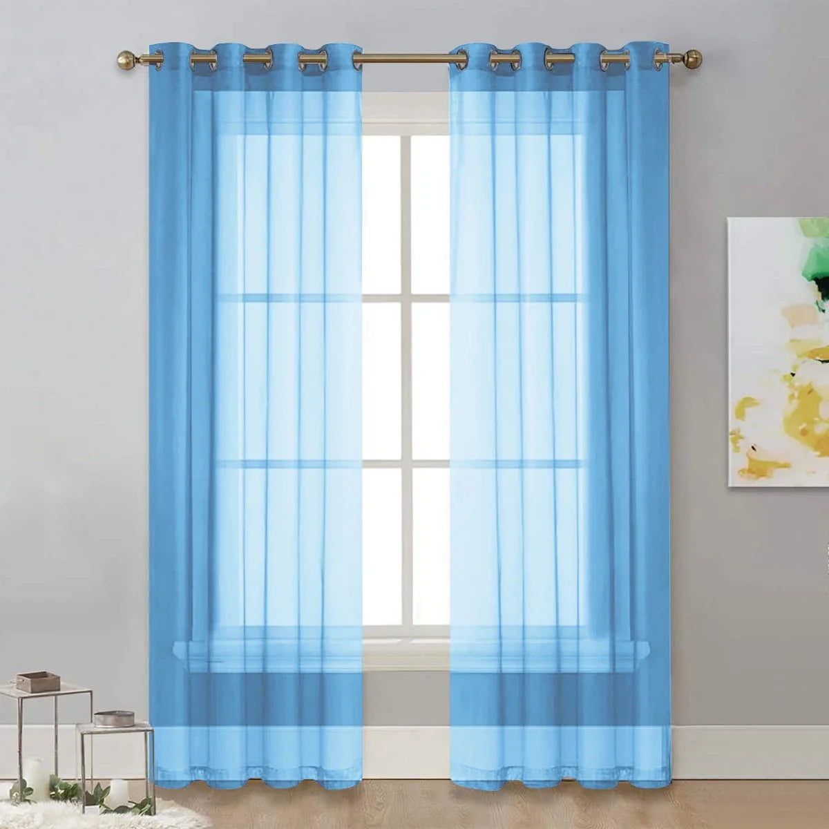 Rideau voilage bleu à œillets dorés habillant une fenêtre, apporte une touche de couleur douce au salon