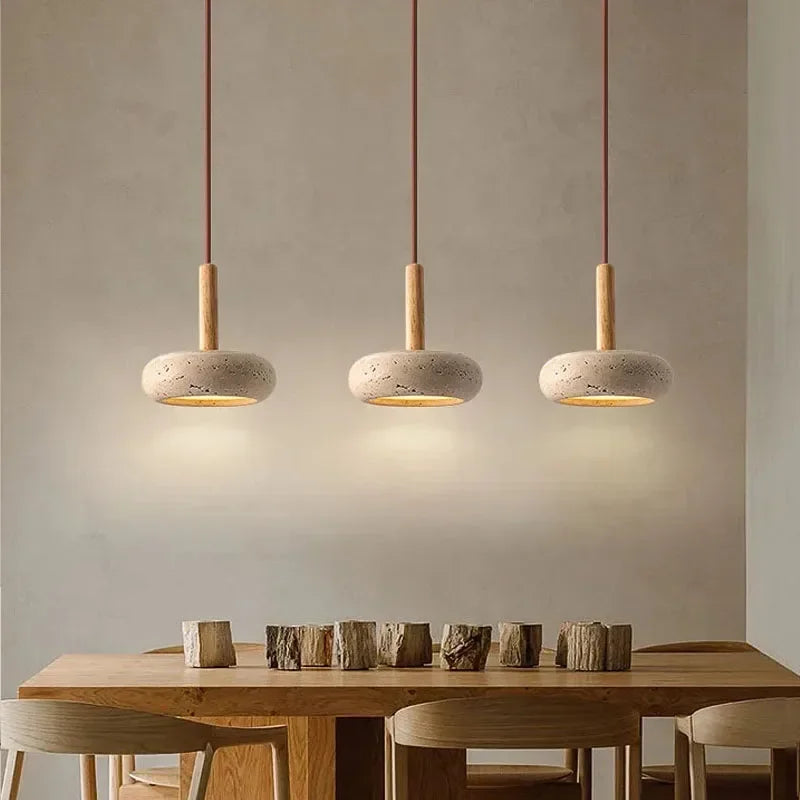 Suspension luminaire en pierre et bois installée au-dessus d’une table en bois.