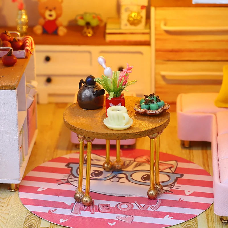 Table de salon miniature avec théière, tasse et décoration sur tapis rond rose