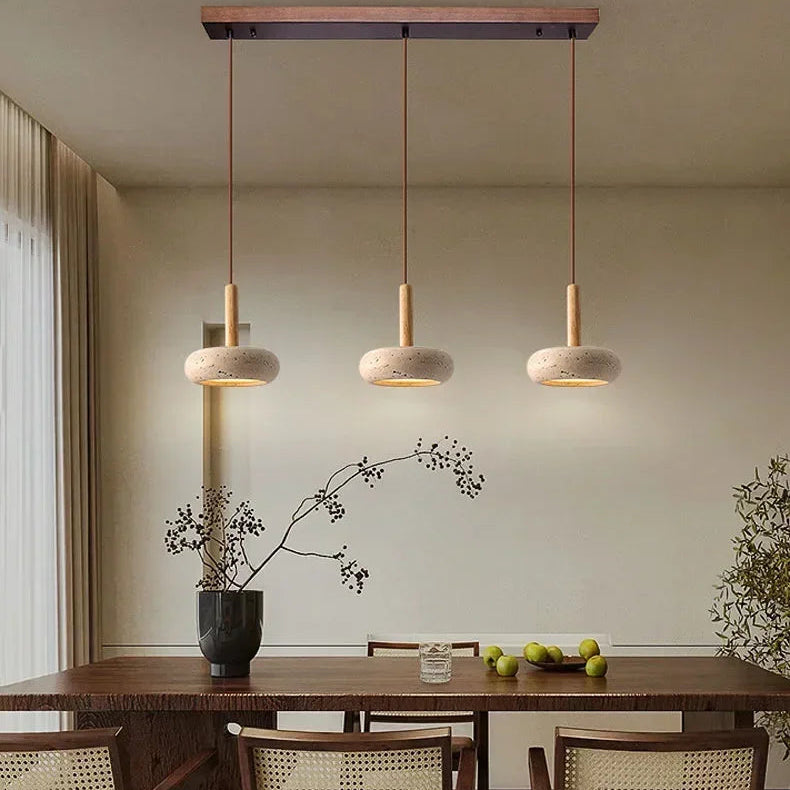 Triple suspension en pierre et bois installée au-dessus d’une table à manger.
